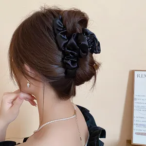Primo piano di una molletta per capelli francese in tessuto nero a pieghe elegante.