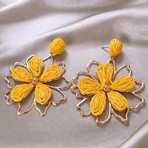 Macro view of Bohemian yellow woven flower earrings with elegant gold metal outlines
