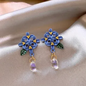Exquisite close-up of blue floral stud earrings with elegant clear crystal teardrop dangles