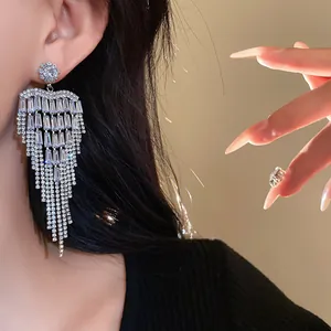 Close-up of silver-tone zircon tassel earrings with heart-shaped stud and fringe