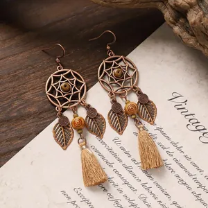 Close-up of bohemian dreamcatcher earrings with leaf charms and khaki tassels.