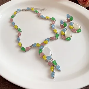 Vista detallada de un dulce conjunto de joyas de resina con capullos de colores y piedras ovales
