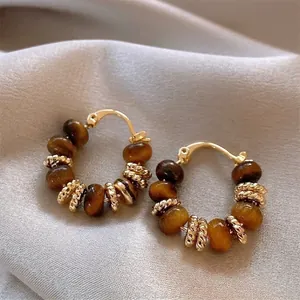 Detailed view of bohemian gold hoop earrings with natural tiger eye beads and spacers