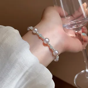 Close-up of a French style pearl and zircon bracelet worn on a wrist holding a wine glass.