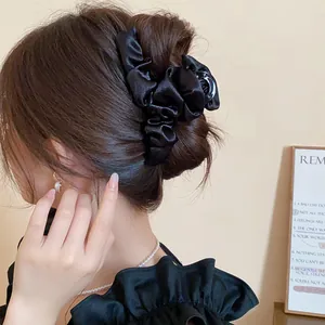 Vista dettagliata di una pinza per capelli francese in tessuto nero a pieghe su uno chignon.