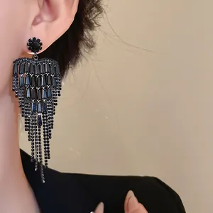 Close-up of elegant black rhinestone tassel heart earrings worn by a model