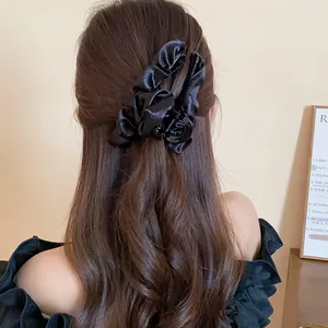 Primo piano di un'elegante molletta per capelli in tessuto nero a pieghe su lunghi capelli castani