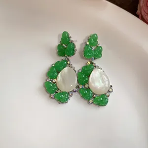 Primer plano detallado de pendientes de capullo en resina verde con perla blanca en gota