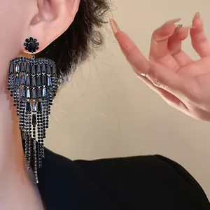 Close-up detail of black zircon tassel earrings worn on ear for evening dress look