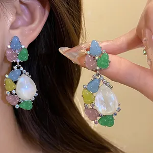 Primer plano de pendientes de brotes de resina de colores con gota nacarada blanca
