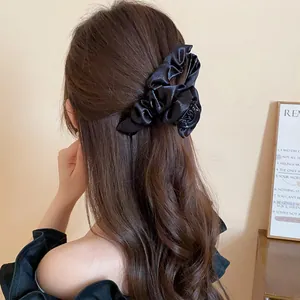 Dettaglio di un fermaglio per capelli vintage in tessuto plissettato nero sui capelli
