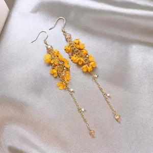 Close-up detail of Bohemian yellow floral drop earrings with gold chains and crystals