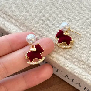 Detalle de cerca de pendientes de caballito de madera rojo flocado con perla y brillantes