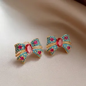 Detailed close-up of bohemian style bow-knot earrings with blue and red crystals