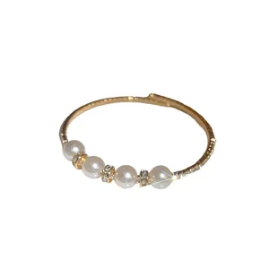 Elegant baroque open bangle with four pearls and pavé crystals on a gold-plated band.