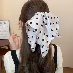 Primer plano de una pinza para el pelo con lazo de tela blanco y lunares negros clásicos