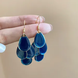 Close-up of bohemian gold hook earrings with layered dark blue teardrop charms.