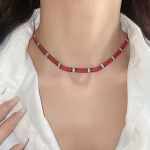 Detalle de un collar choker geométrico con patrón de serpiente rojo y negro de estilo vintage