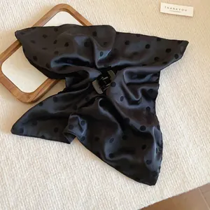 Primer plano de una pinza para el pelo de tela con lunares negros de estilo retro.