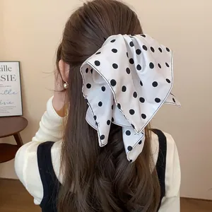 Pinza para el pelo retro de tela blanca con lunares negros y un lazo grande.