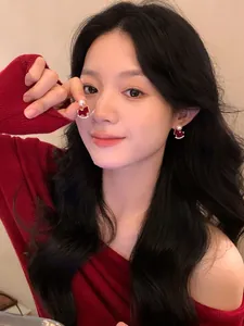 Elegantes pendientes de caballo flocados en rojo con perlas y cristales en una modelo