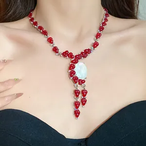 Primer plano de collar de resina roja con flores y piedra ovalada blanca