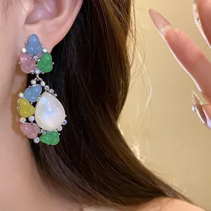 Detalle de pendientes colgantes de resina de colores con piedra blanca en forma de pera