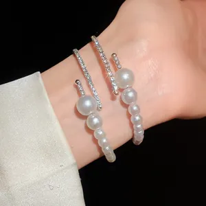 Close-up detail of a silver-toned open bangle featuring lustrous pearls and rhinestones