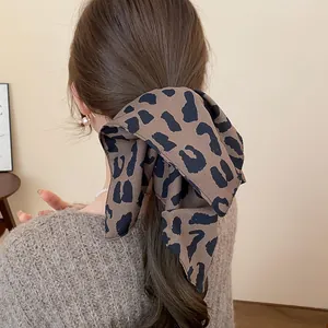 Detalle de una pinza para el pelo con lazo de leopardo retro en cabello castaño