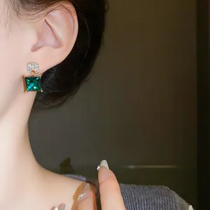 Close-up of vintage geometric earrings with sparkling green crystal and silver needle