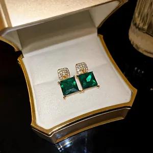 Close-up of vintage luxury emerald green square crystal stud earrings in a gift box