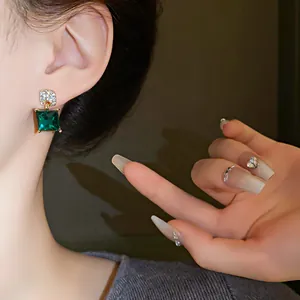 Close-up of elegant green square crystal earrings with diamond-encrusted silver studs