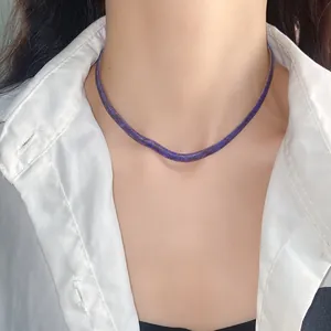 Vista detallada de un collar plano con patrón de serpiente púrpura usado por una modelo