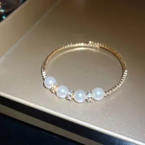 Detailed close-up of a gold baroque bangle with four pearls and sparkling rhinestones