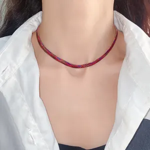 Primer plano de una gargantilla roja con estampado de serpiente y camisa blanca.
