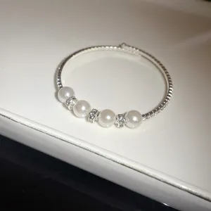 Elegant silver open bangle featuring four pearls and sparkling rhinestone details
