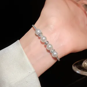 Close-up of an elegant silver-toned bracelet with white pearls and rhinestones on a wrist.