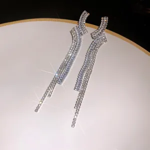 Close-up detail of shimmering silver zircon irregular geometric long tassel earrings