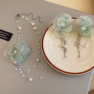 Detail view of green mesh flower necklace and earrings set with pearls and zircons