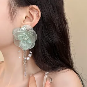 Detail view of fairy-style green mesh flower earrings with pearls on model