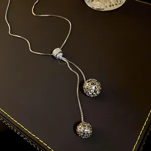 Close-up of adjustable stainless steel sweater chain with hollow rhinestone globes.