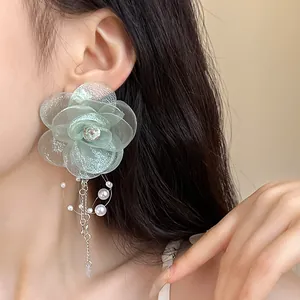 Close-up of elegant green mesh flower earring with pearls and zircons worn on ear