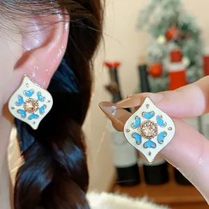 Close-up of vintage-style enamel earrings with blue heart patterns and rhinestone