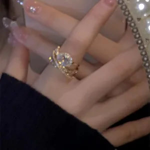 Nahaufnahme eines eleganten vergoldeten Zirkonrings am Finger bei weichem Licht