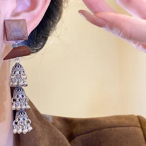 Close-up detail of vintage bohemian style wood and hollow silver tassel earrings