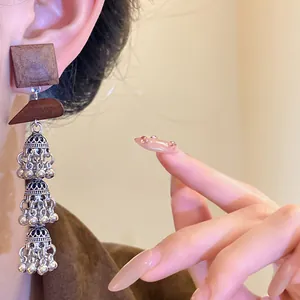 Close-up of vintage ethnic wood and hollow silver tassel jhumka earrings detail view