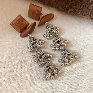 Close-up of vintage wood square earrings with silver bell tassels in Bohemian style.
