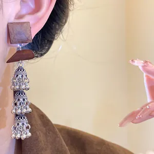 Close-up of vintage ethnic wooden square earrings with triple tier hollow silver tassels