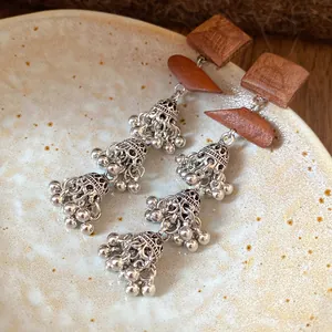 Close-up detail of vintage Bohemian wooden square stud with silver-tone hollow bell tassels.