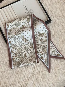 Detailed close-up of an elegant cream silk scarf featuring a classic brown paisley pattern